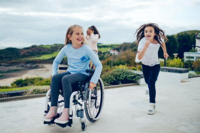 Kinder spielen im Rollstuhl in München draußen